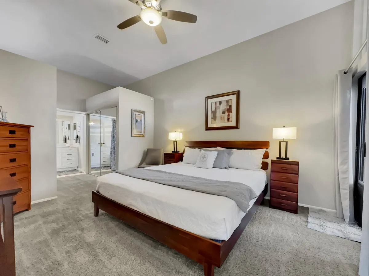 This image showcases a serene bedroom featuring a comfortable bed, nightstands, tasteful artwork, and a dresser. The space is well-lit, feels spacious, and has a calming color palette, emphasizing relaxation and privacy.